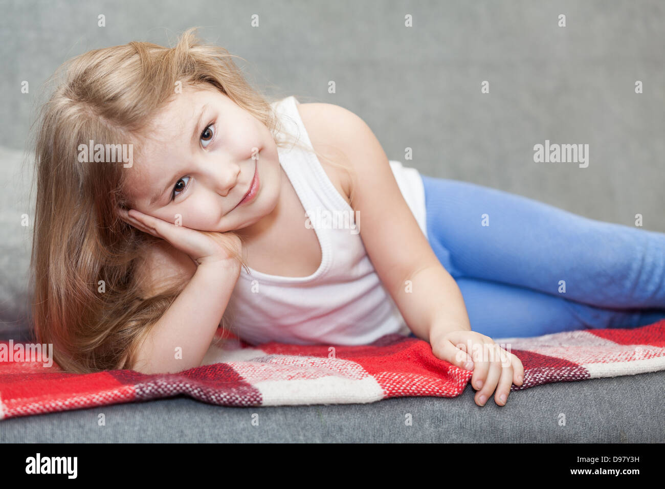 Pretty Caucasian petite fille couchée sur le canapé Banque D'Images