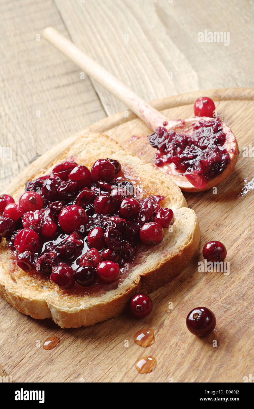 L'une des tartines avec de la confiture de canneberges sur table en bois Banque D'Images