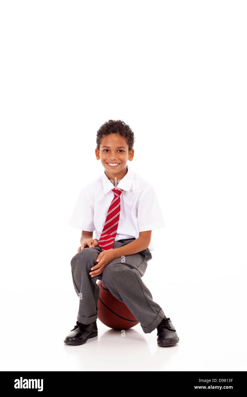 Cute little primary schoolboy assis sur basket ball on white Banque D'Images