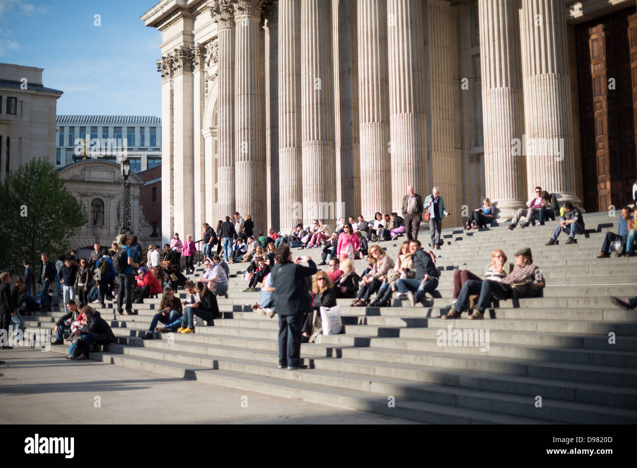 St Paul's Cathedral People on Steps Londres Angleterre // LONDRES, Angleterre — les gens sont assis sur les marches de la cathédrale St Paul, l'un des monuments les plus distinctifs de Londres. La cathédrale se trouve sur un site qui abrite une église depuis 604 après JC, bien que la structure actuelle ait été conçue par Sir Christopher Wren à la suite du Grand incendie de Londres. Achevée entre 1675 et 1710, la cathédrale est réputée pour son dôme massif qui domine l'horizon londonien. St Paul a servi de cadre à de nombreux événements importants dans l'histoire britannique, y compris le mariage du prince Charles et de Lady Diana Spen Banque D'Images