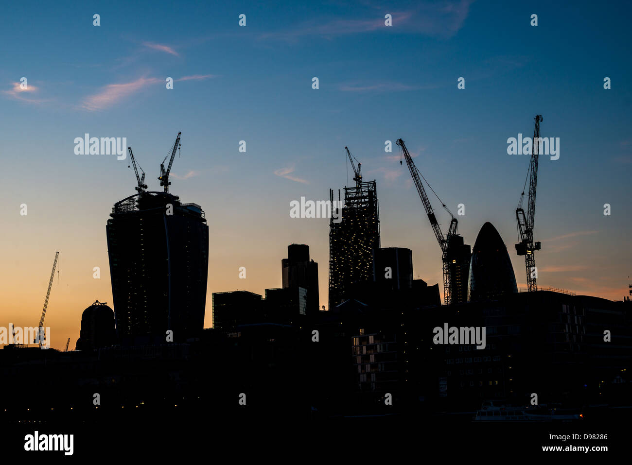 London Skyline construction Silhouette Londres // LONDRES, Royaume-Uni — L'évolution de la skyline de Londres se dessine de façon spectaculaire sur un ciel sombre, mettant en valeur la construction en cours de nouveaux gratte-ciel. Cette image saisissante reflète la croissance dynamique et l'ambition architecturale de la ville, avec les contours des immeubles en hauteur émergeants qui côtoient des monuments établis, symbolisant la transformation continue de Londres en tant que centre financier et culturel mondial. Banque D'Images