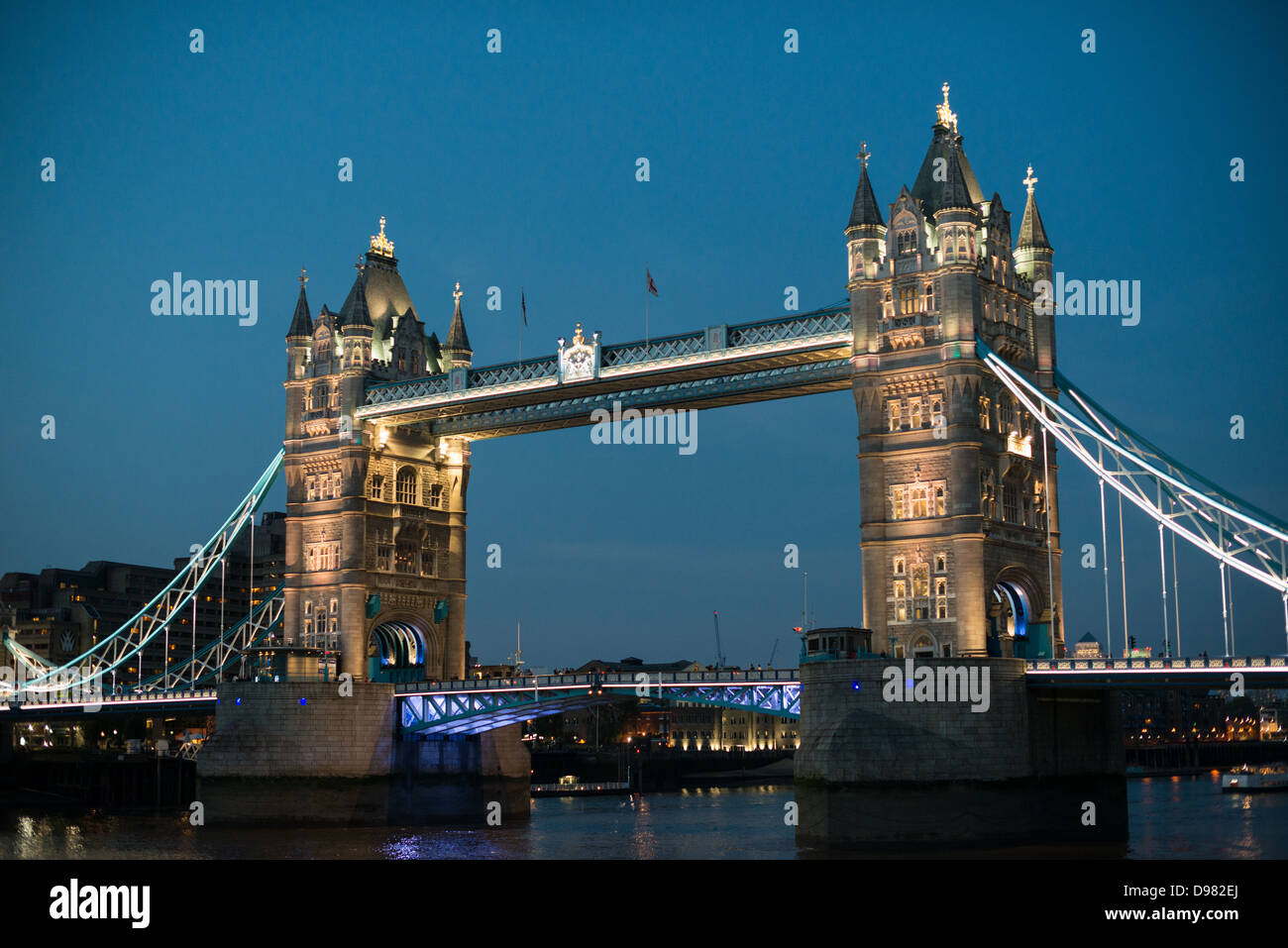 Tower Bridge au crépuscule Londres // LONDRES, Royaume-Uni — L'emblématique Tower Bridge enjambe la Tamise au crépuscule, ses tours gothiques victoriennes illuminées contre le ciel du soir. Achevé en 1894, ce pont suspendu et basculant relie la ville de Londres à Southwark sur la rive sud. Le pont tire son nom de la Tour de Londres, un château historique et ancienne résidence royale. Tower Bridge comprend deux tours de 213 pieds reliées par deux passerelles horizontales et une paire de routes mobiles qui peuvent être surélevées pour permettre le passage de la circulation fluviale. Il reste l'un des plus londoniens Banque D'Images