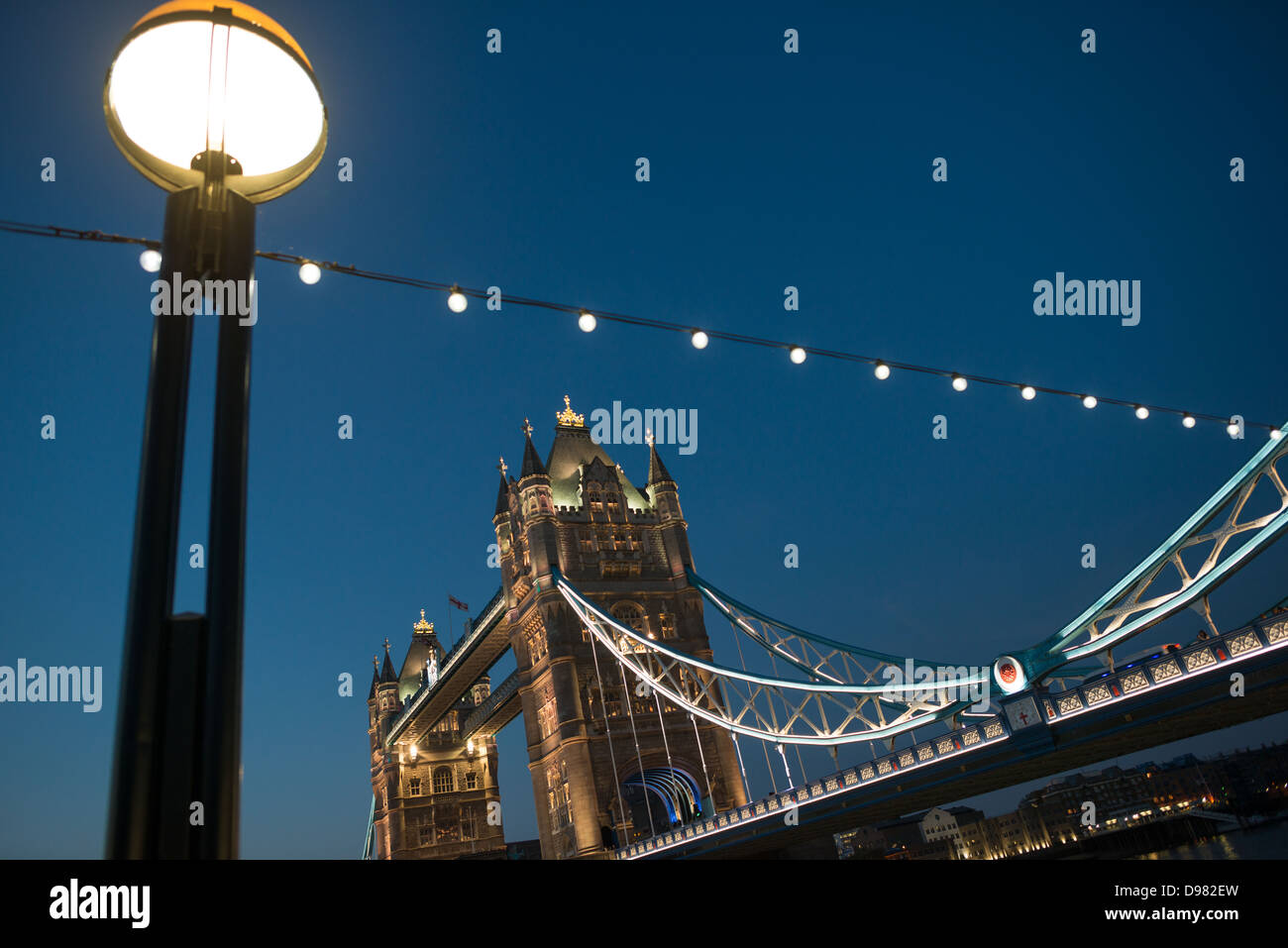 LONDRES, Royaume-Uni — le célèbre Tower Bridge de Londres au crépuscule. Construit à la fin des années 1800, le Tower Bridge orné est l'un des monuments emblématiques de Londres. Elle tire son nom de la tour de Londres, située à proximité, sur la rive nord de la Tamise. Au premier plan se trouvent les lumières de Queen's Way, sur la rive sud de la Tamise. Banque D'Images