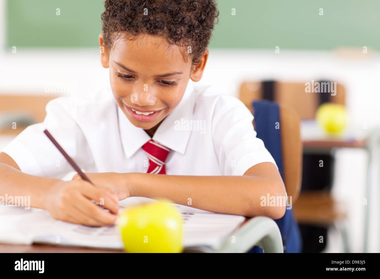 Primary schoolboy occupés à écrire le travail en classe Banque D'Images