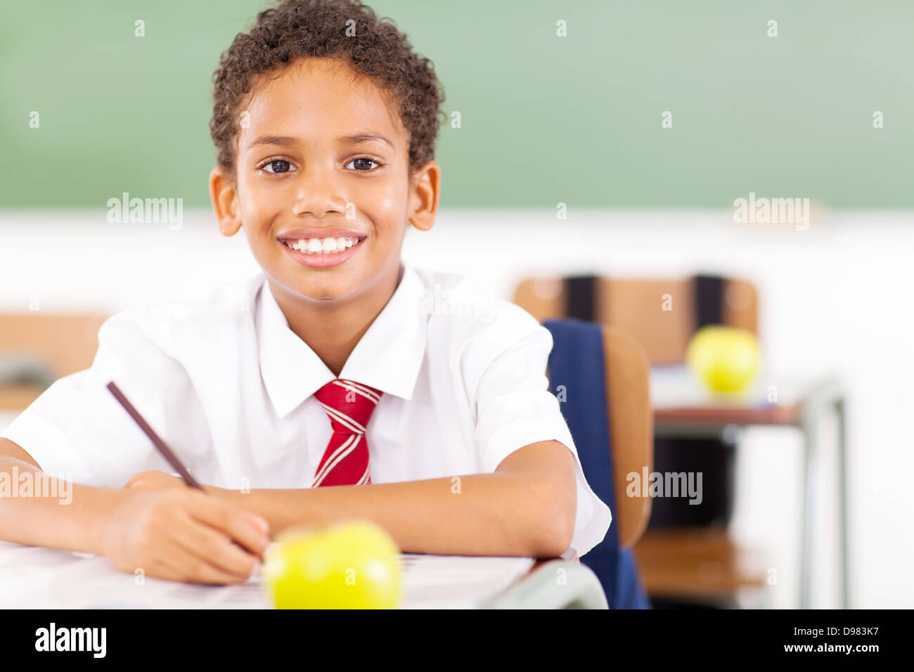 Heureux écolier du primaire en classe d'écriture Banque D'Images