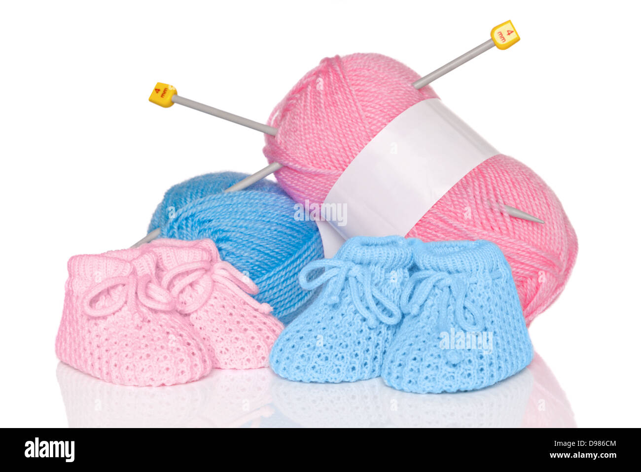 Chaussons pour bébé tricotés avec la laine rose et bleu et des aiguilles à tricoter, isolé sur un fond blanc. Banque D'Images