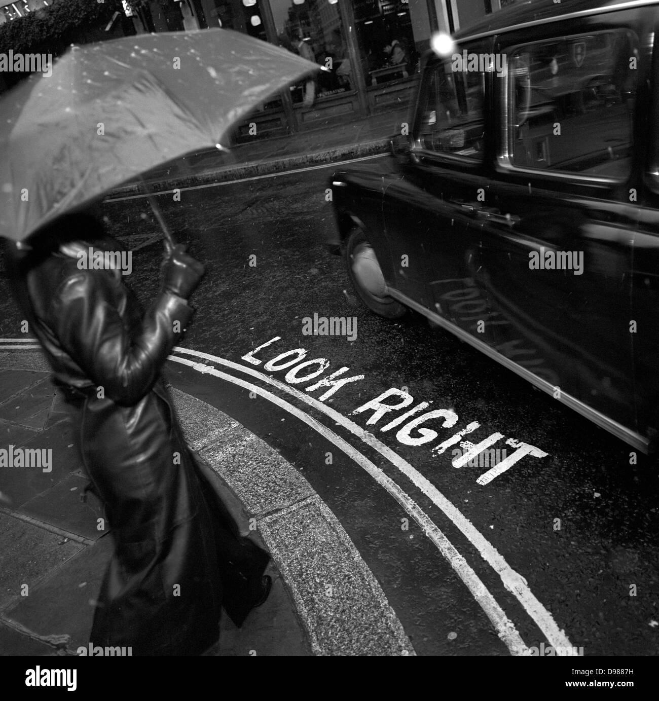 Un piéton est sur le point d'étape sur une rue du centre de Londres, en traversant les mots Regardez à droite comme un taxi tourne à gauche. Vu en noir et blanc, nous voyons des flocons gelés par flash sur ce coin de rue urbaine dans la ville de Londres, au cœur de la capitale, le quartier financier. Le stencil marcheurs mots racontent à regarder les voitures venant en sens inverse, lorsqu'il n'est pas facile de ne pas se concentrer et la cause de nombreuses blessures (principalement pour les touristes) à ceux qui ne sont pas utilisées pour le trafic sur le côté opposé de la route pour le reste de l'Europe. Banque D'Images