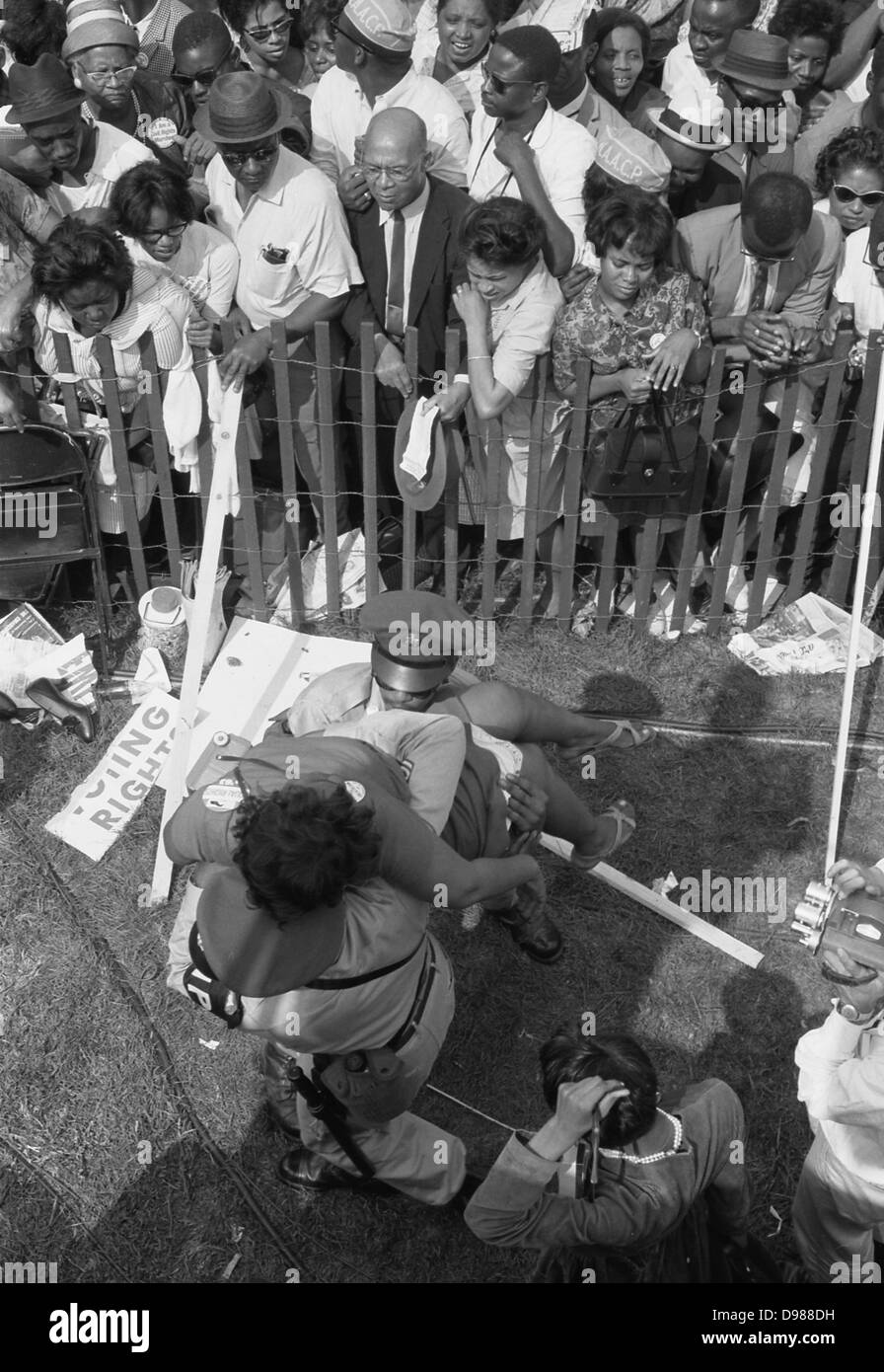 Manifestation à Washington, D.C. photographie montre une foule d'Américains africains derrière une clôture de tempête avec la police transportant une femme de l'autre côté, 28 août 1963. Marion S.Trikosko, photographe. Banque D'Images