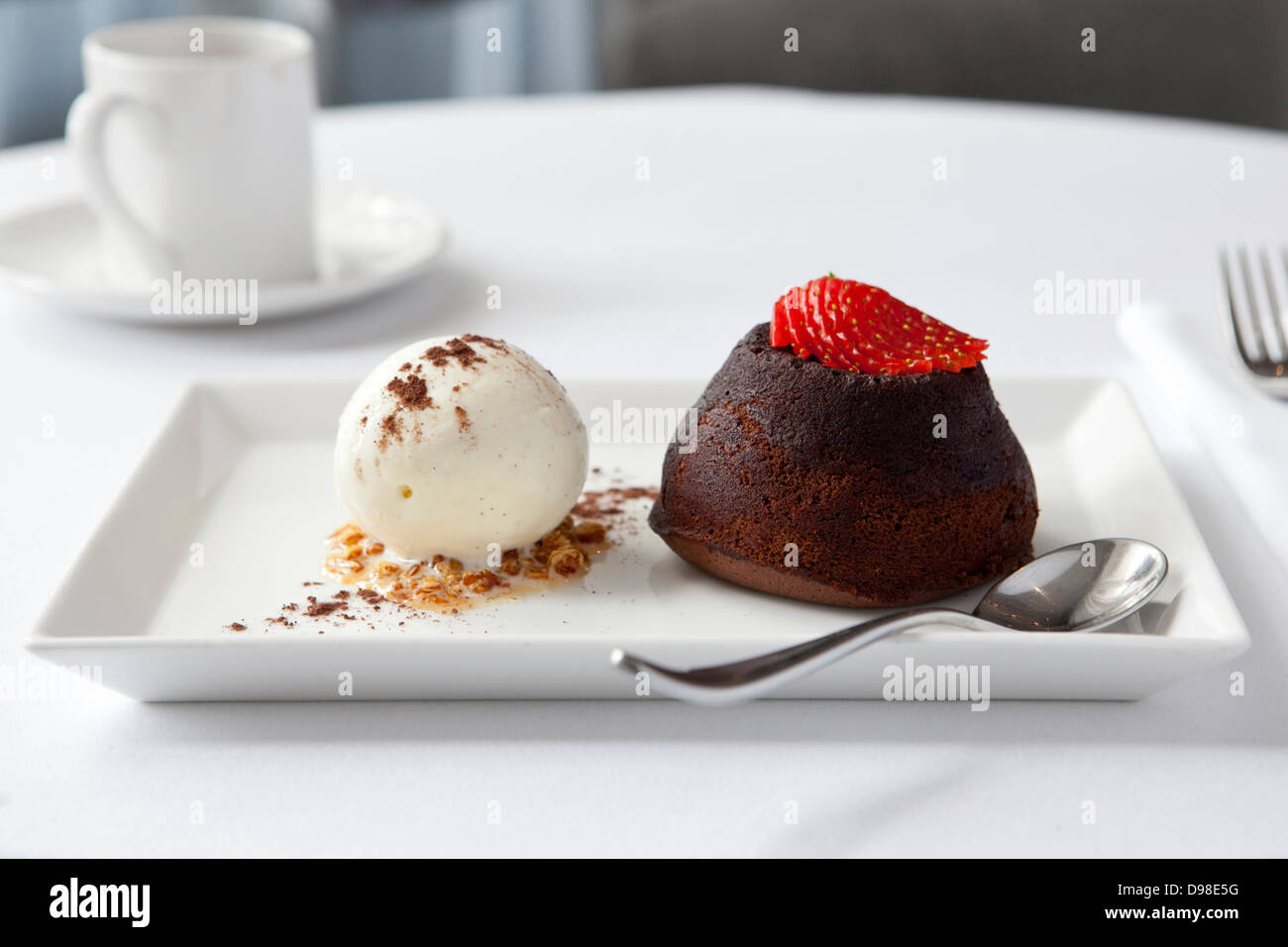 Fondant au chocolat surmontée d'une fraise, glace vanille Banque D'Images