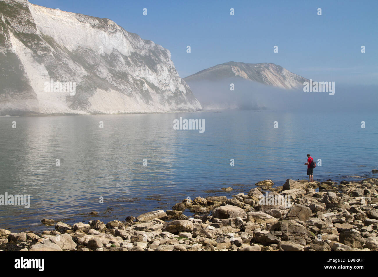 L'homme pêche sur la côte du Dorset, Angleterre. Banque D'Images