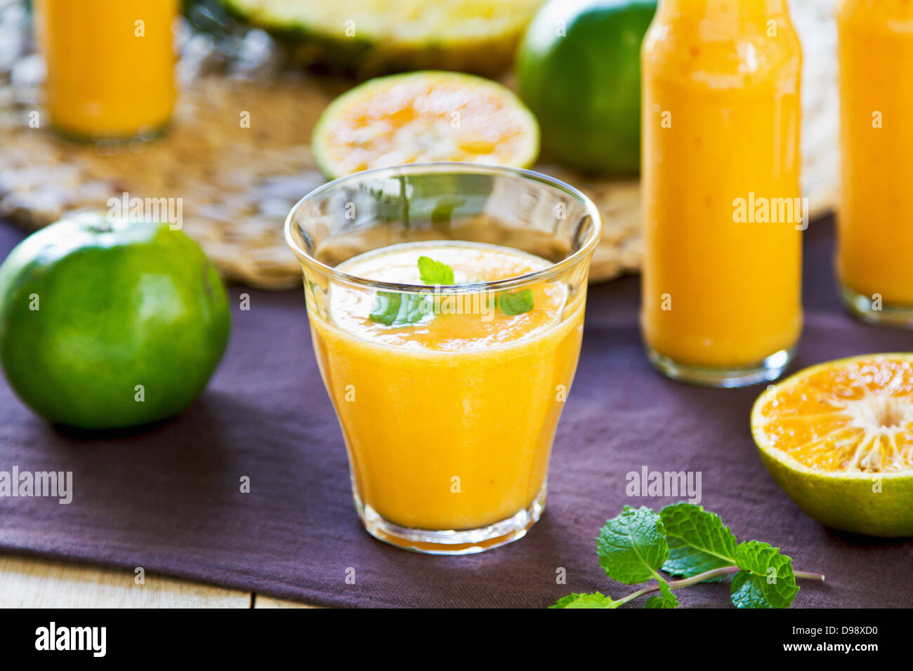 Avec Orange ananas et mangue smoothie dans un verre et bouteilles Banque D'Images