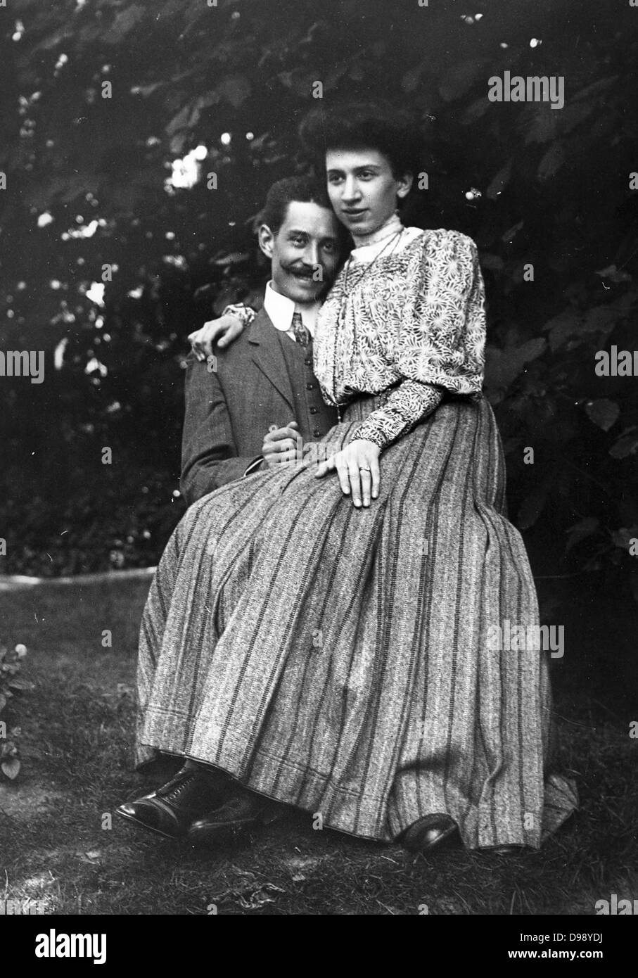Jeune couple marié, assis ensemble dans un jardin, circa 1900 Banque D'Images