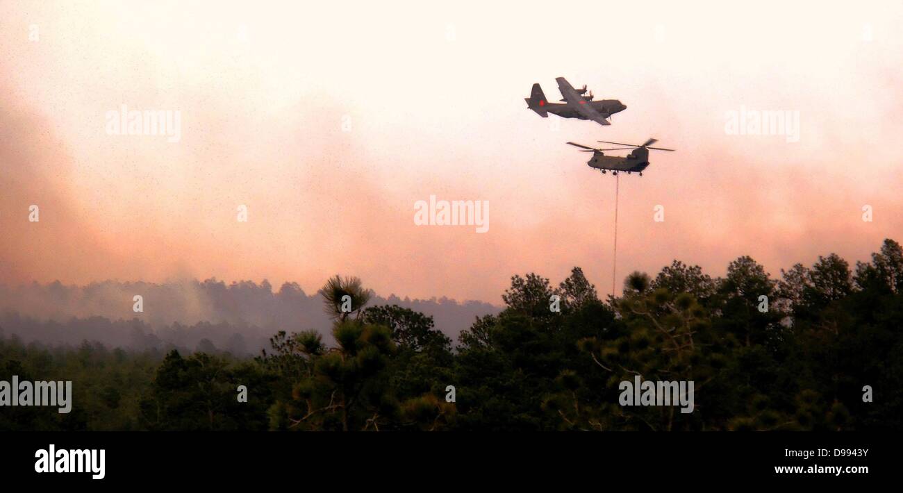 Un C-130 équipé d'incendie complète une goutte comme un hélicoptère Chinook, déverse l'eau sur le Feu de Forêt Noire le 12 juin 2013 près de Colorado Spring Co., l'incendie a tué deux personnes et détruit plus de 500 maisons de plus en plus destructrices de l'incendie dans le Colorado. Banque D'Images