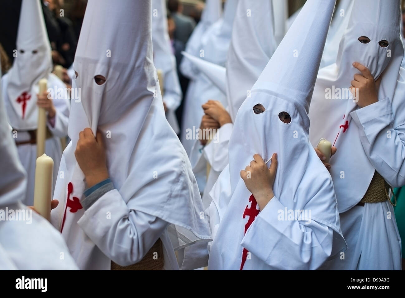 Les enfants vêtus de robes de pénitence et capots de participer à une Semaine Sainte de Séville, Espagne. Banque D'Images