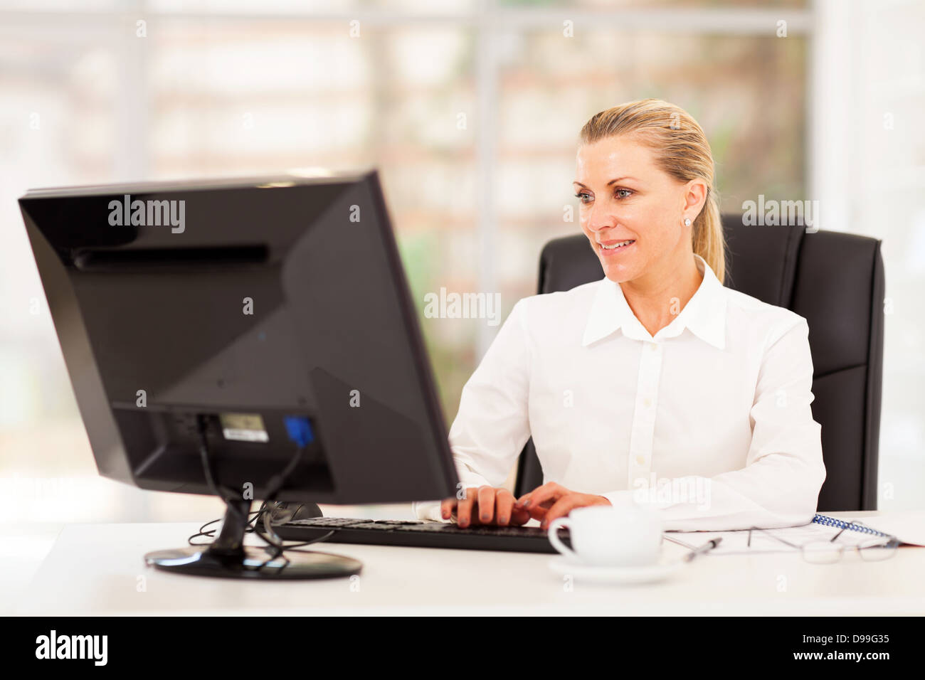 Middle aged female office worker working on computer Banque D'Images