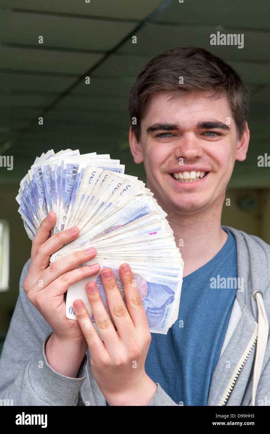 Heureux Jeune homme tenant un fan de notes de 20 livres pour un total de trois mille livres Banque D'Images
