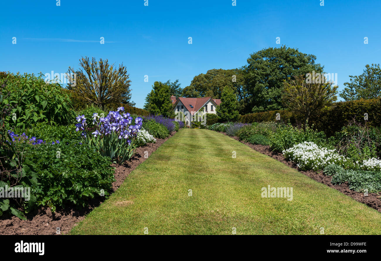 Kenton, Devon, Angleterre. 4 juin 2013. Jardin traditionnel anglais border menant à une maison à la campagne. Banque D'Images