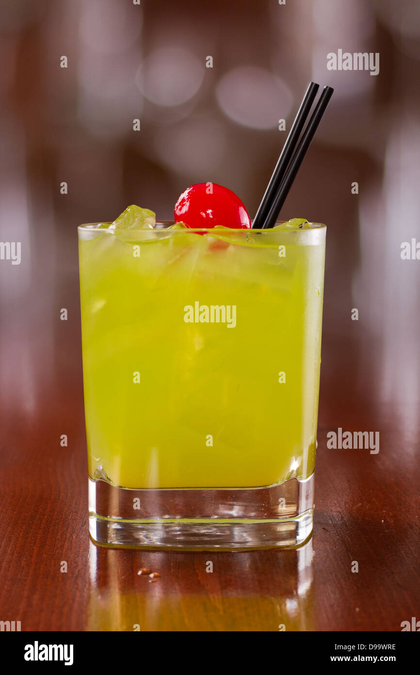 Cocktail vert vif servi sur un poste occupé hors foyer bar avec une cerise rouge servi sur les rochers Banque D'Images