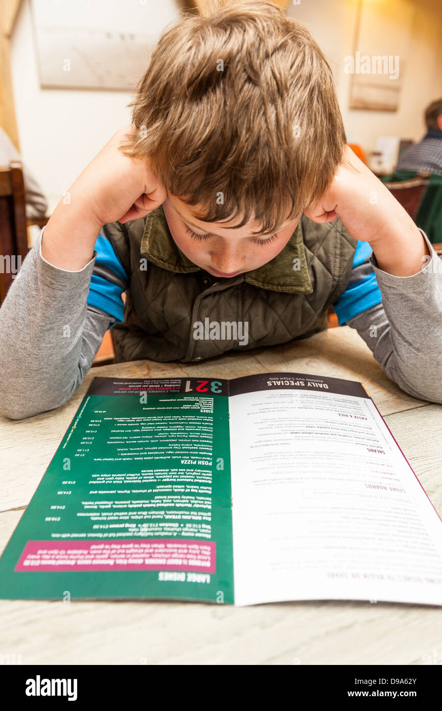 Un garçon de 9 ans regarde le menu dans Byfords cafe à Holt , Norfolk , Angleterre , Angleterre , Royaume-Uni Banque D'Images