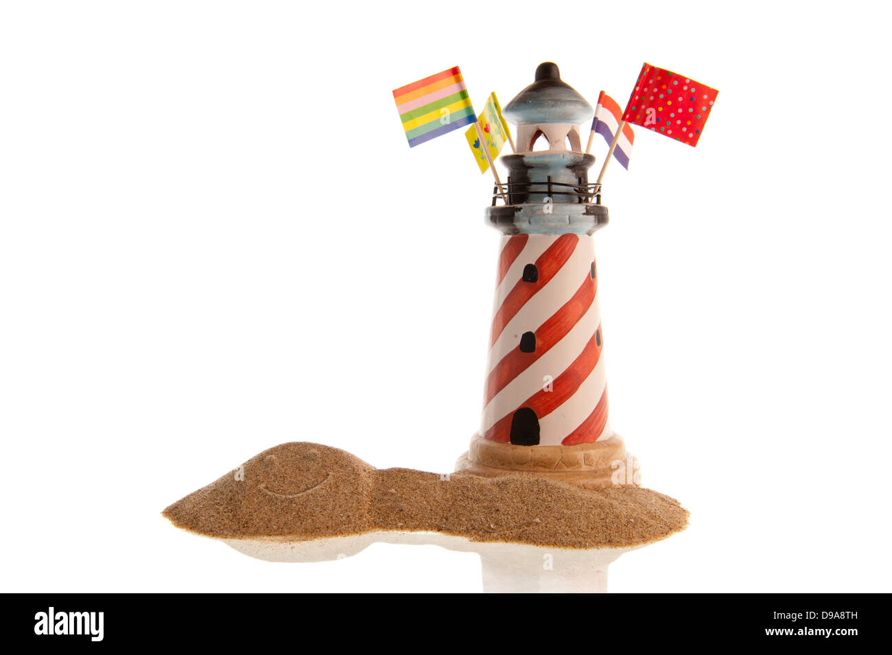 Phare rayé rouge avec un assortiment de drapeaux et d'un smiley dans un tas de sable, en libre et isolé en blanc Banque D'Images