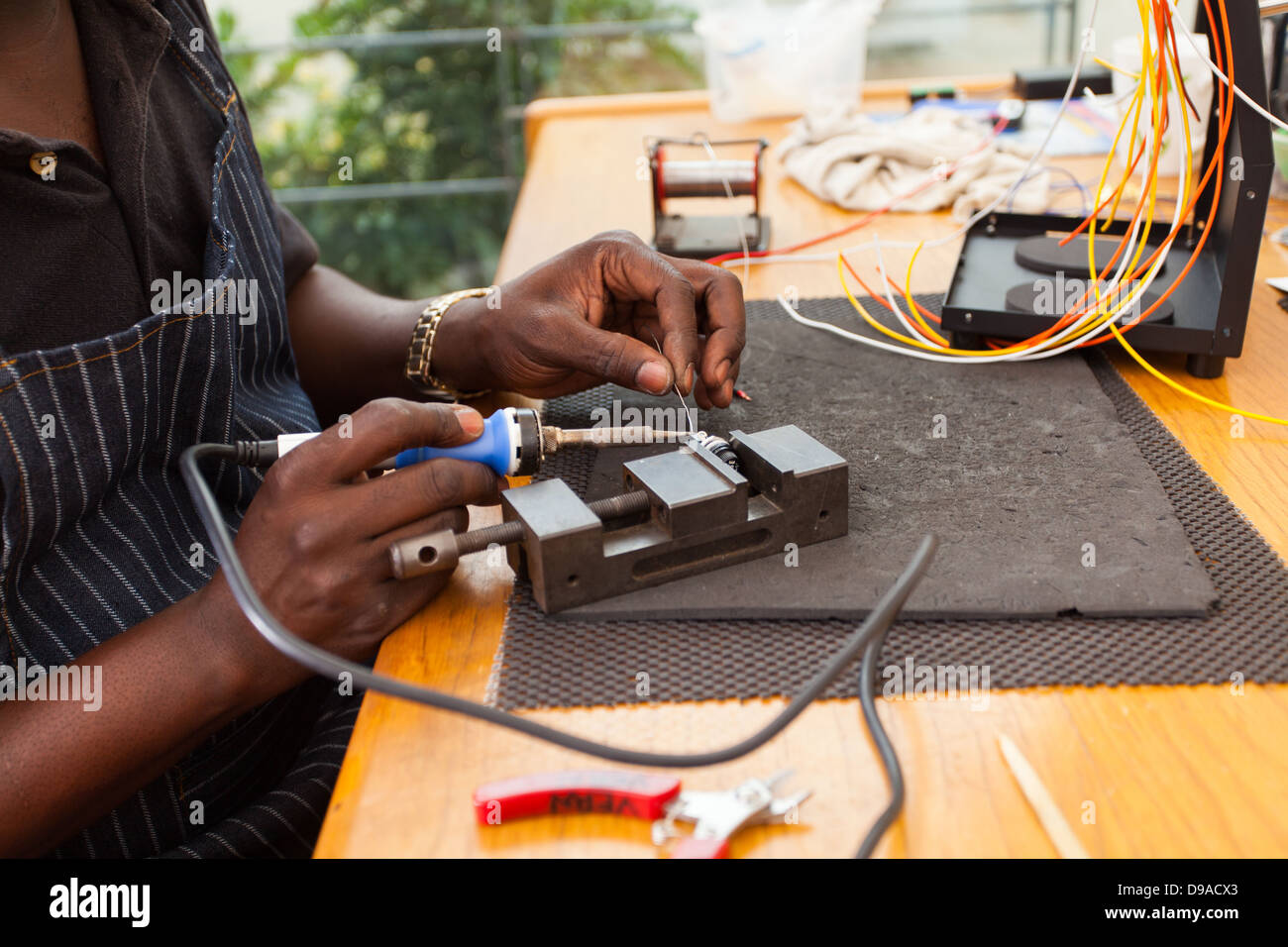 Électricien africains à l'aide de fers à réparer un bouton poussoir Banque D'Images