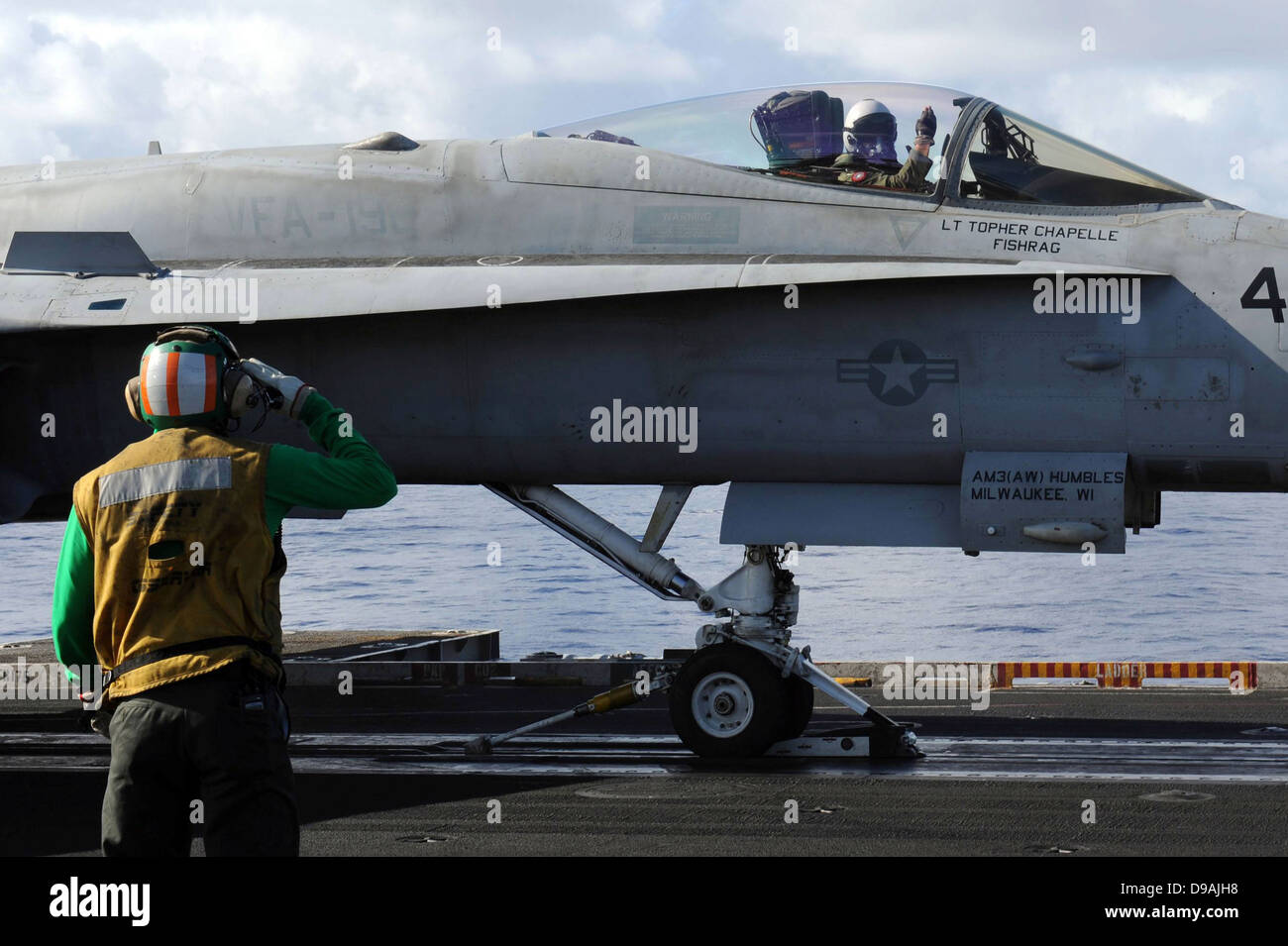L'Aviation de l'US Navy un manoeuvrier salue un F/A-18 pilote avant de décoller sur le pont du porte-avions USS John C. Stennis Avril 24,2013 opérant dans l'océan Pacifique. Banque D'Images
