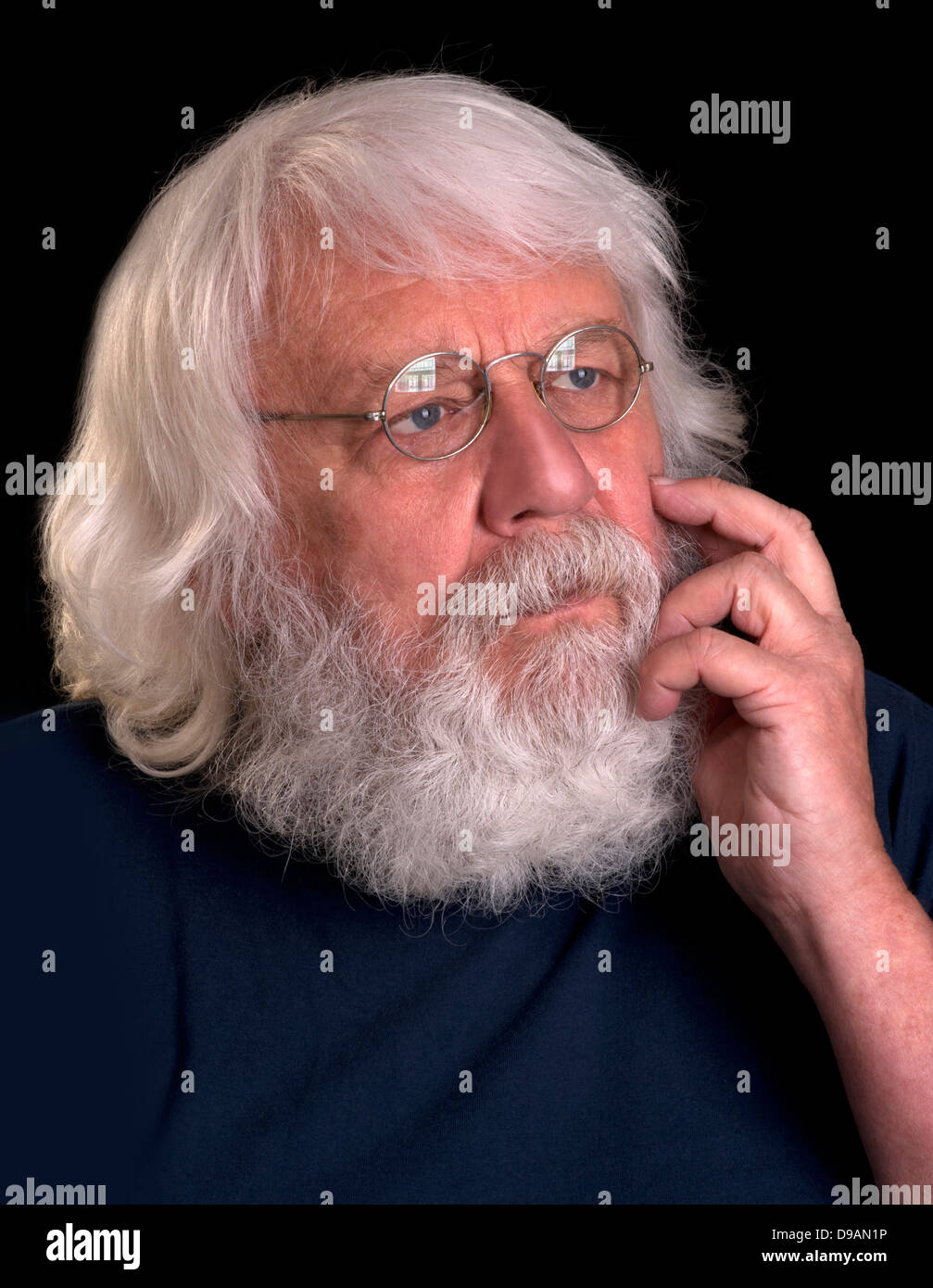 Vieil homme avec barbe complète et verres pensée avec sa main au menton Banque D'Images