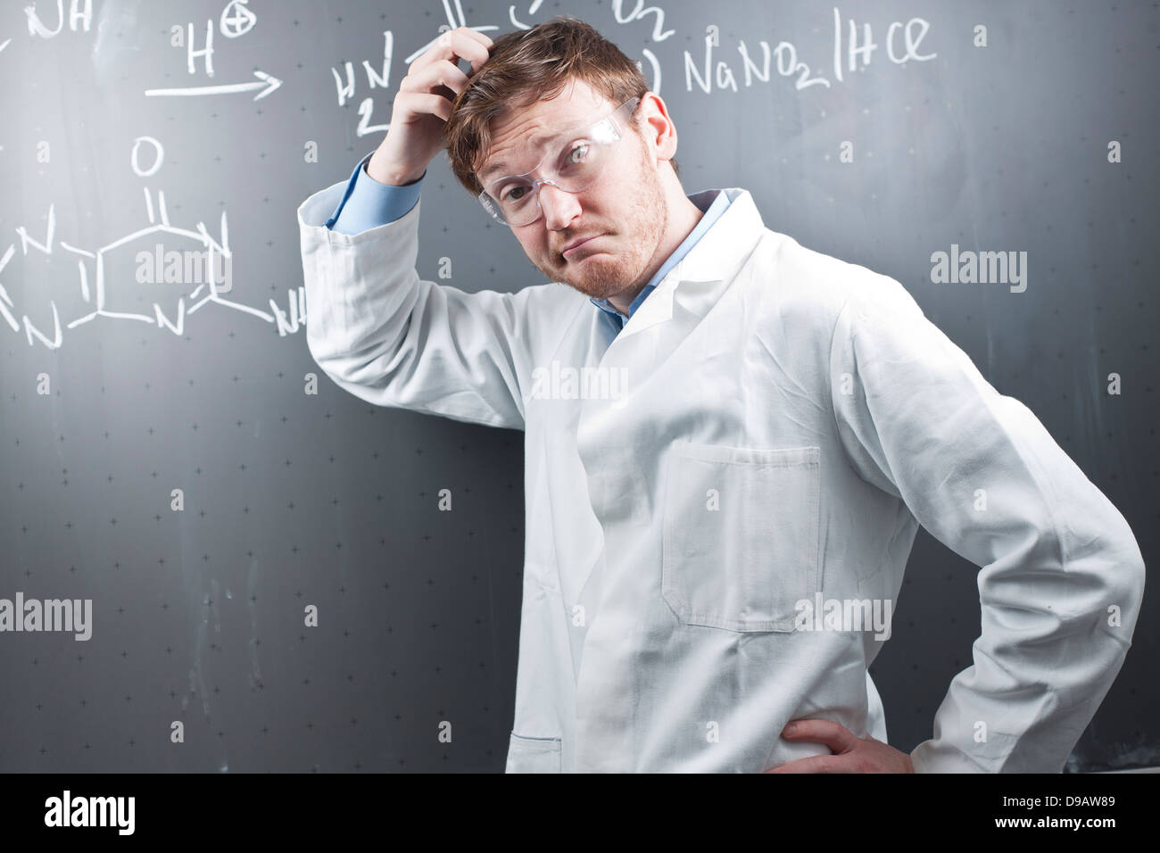 Allemagne, jeune scientifique avec pluzzled l'expression du visage et de l'équation chimique sur tableau Banque D'Images