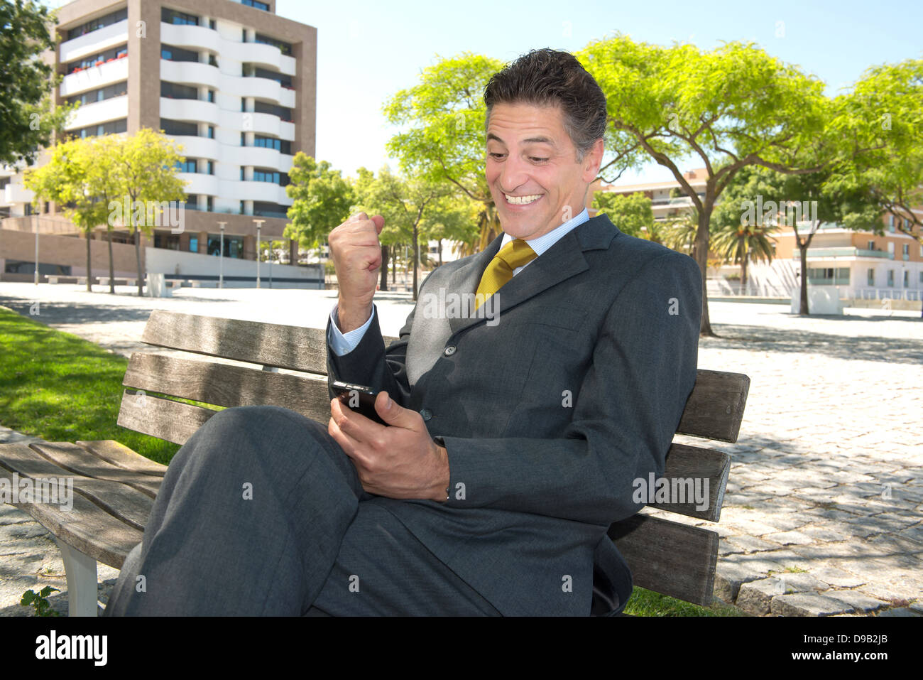 Portrait dans un banc de parc avec cellphone Banque D'Images