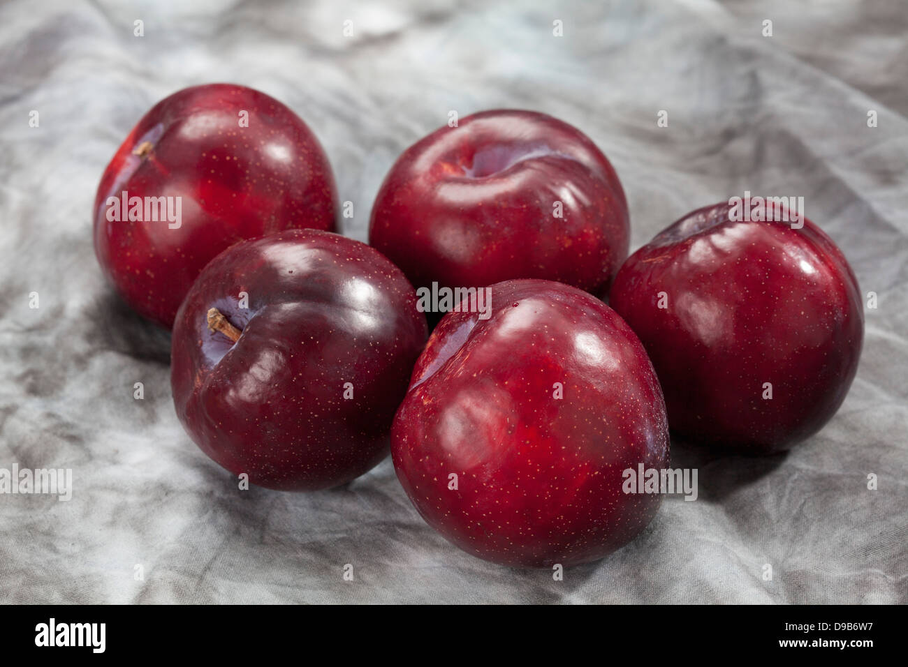 Prunes rouges sur fond gris, Close up Banque D'Images