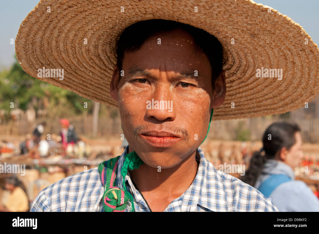 Birman jeune homme portant un chapeau de paille et de mâcher de la noix de  bétel dans un marché encombré le Myanmar (Birmanie Photo Stock - Alamy