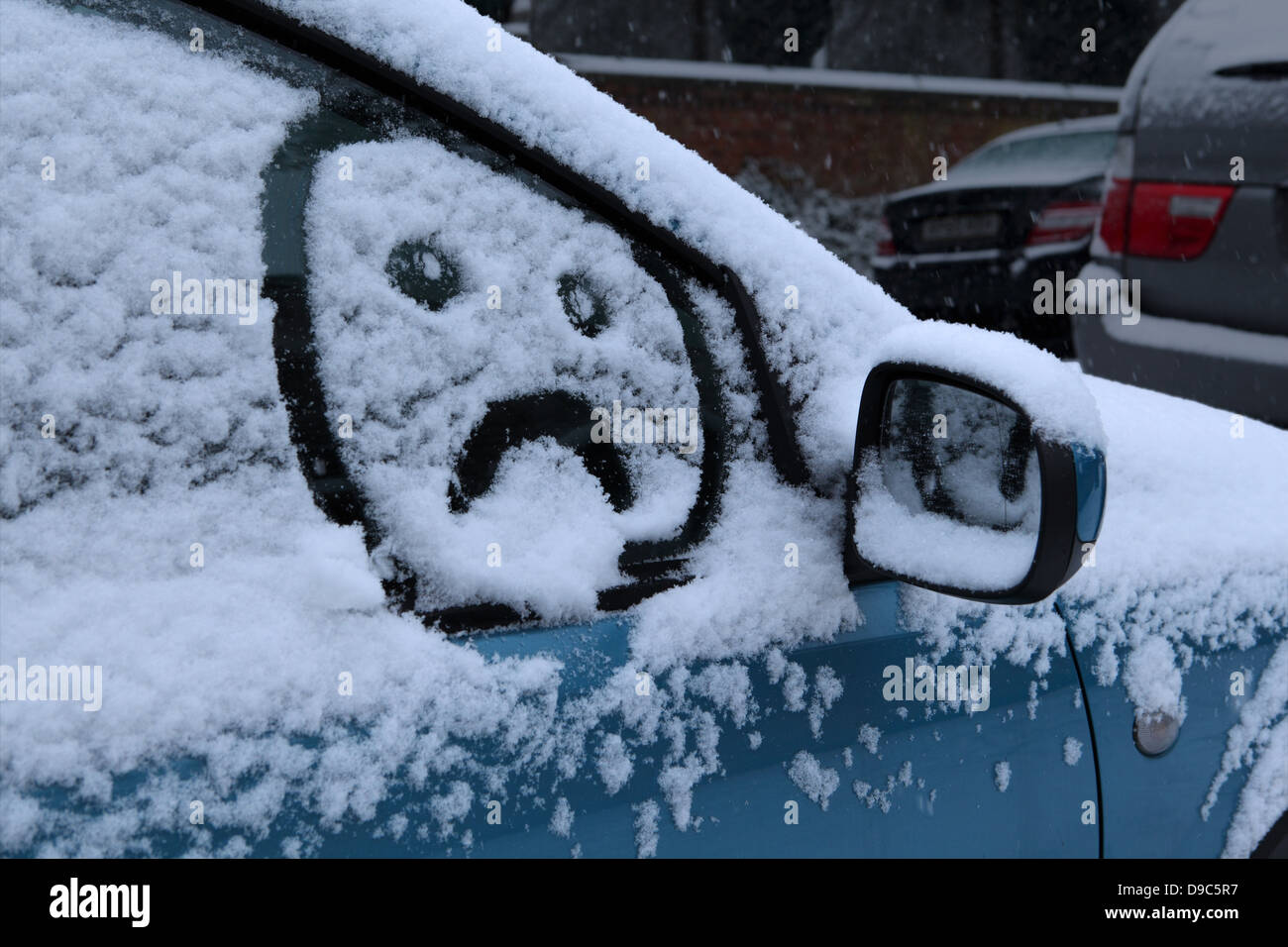 Visage triste dessiné dans la neige sur le pare-brise de voiture Banque D'Images