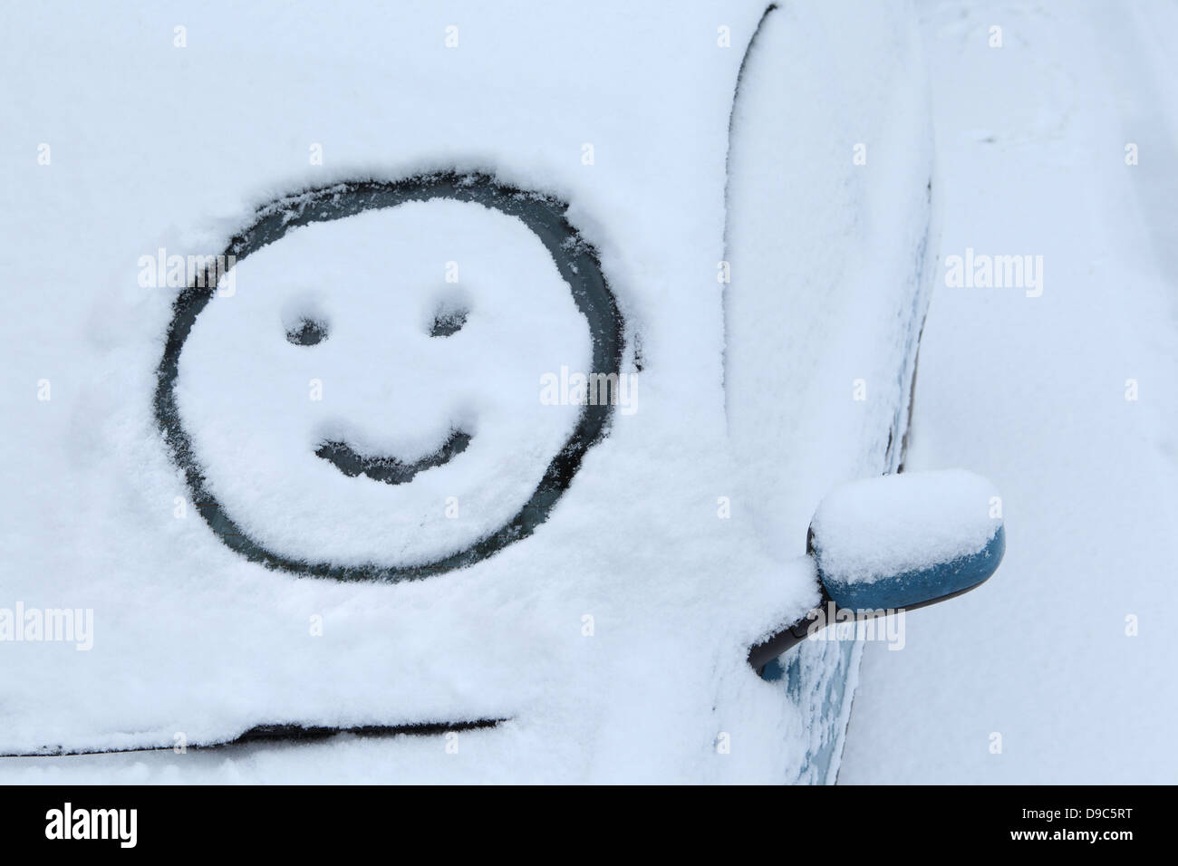 Smiley dessiné dans la neige sur le pare-brise de voiture Banque D'Images