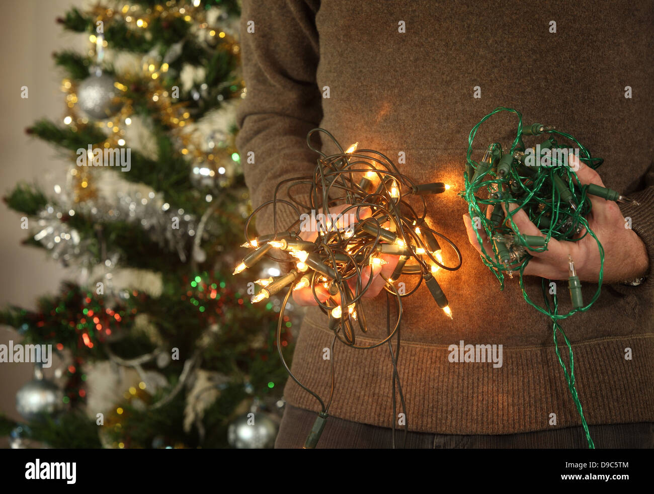 Mâle mature tenant des lumières d'arbre de Noël Banque D'Images