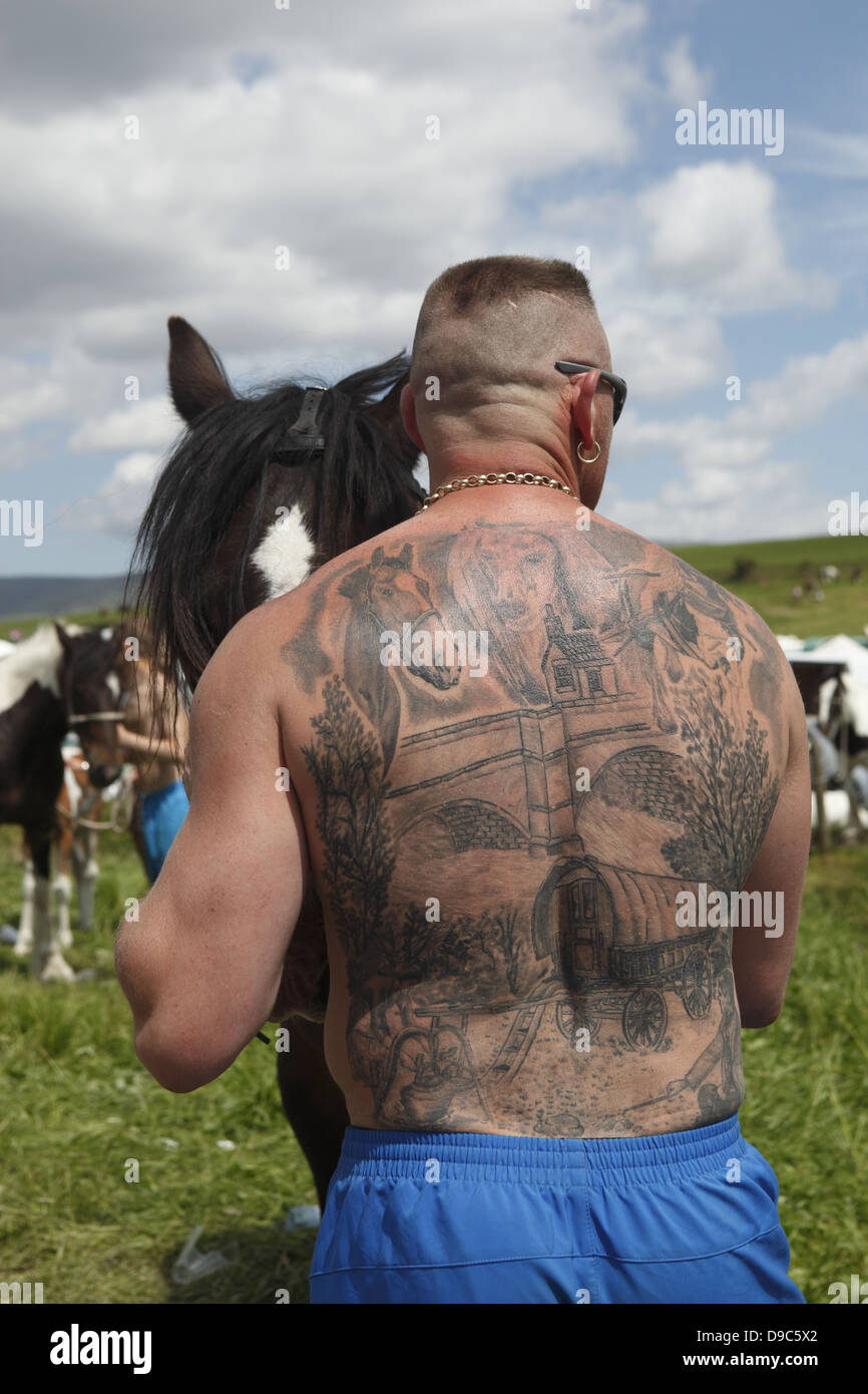 Un homme gitane révèle un tatouage sur son dos qui dépeint la vie tsigane au cours de Appleby Horse Fair, en Cumbria, Angleterre Banque D'Images