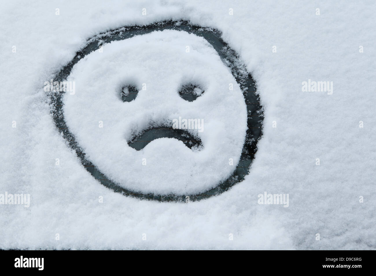 Visage triste dessiné dans la neige Banque D'Images
