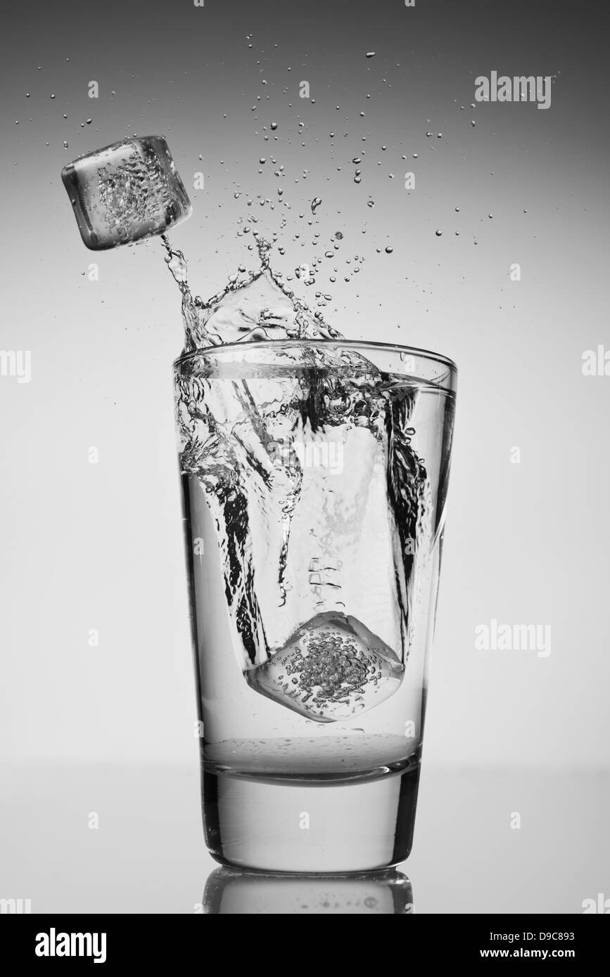 Des cubes de glace tomber dans verre d'eau Banque D'Images