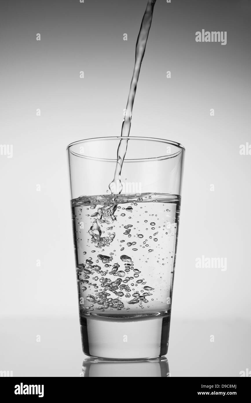 L'eau est versée dans le verre de boisson Banque D'Images