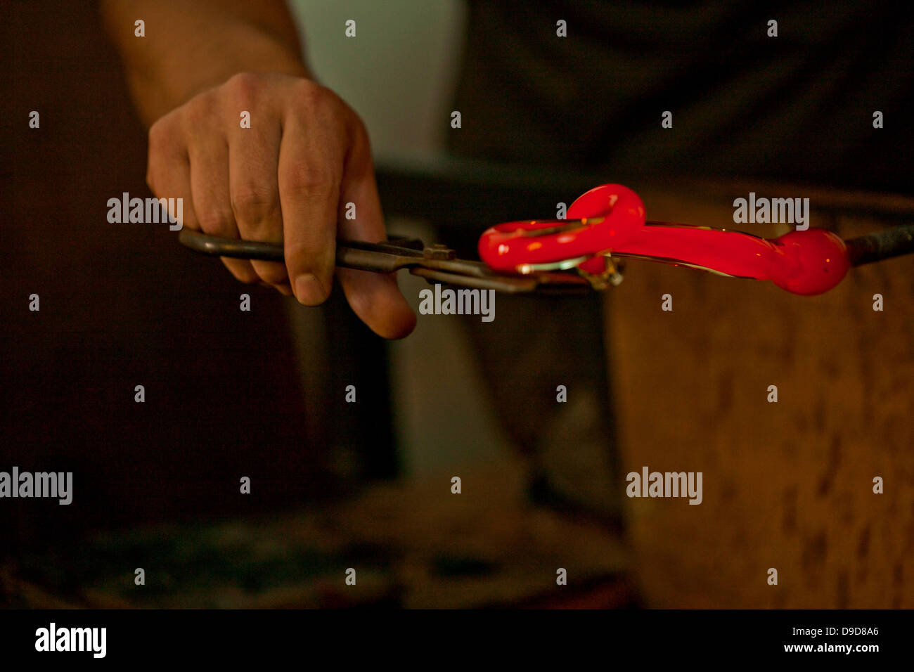 Personne tenant red hot glass en usine Banque D'Images