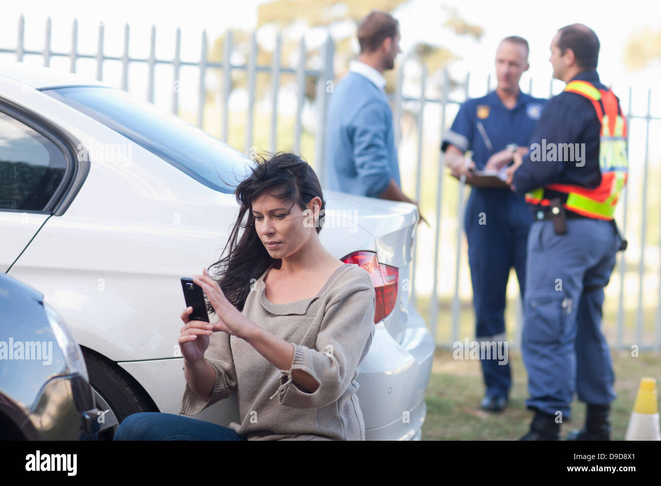 Femme photographiant dégâts sur sa voiture au lieu de l'accident de voiture Banque D'Images