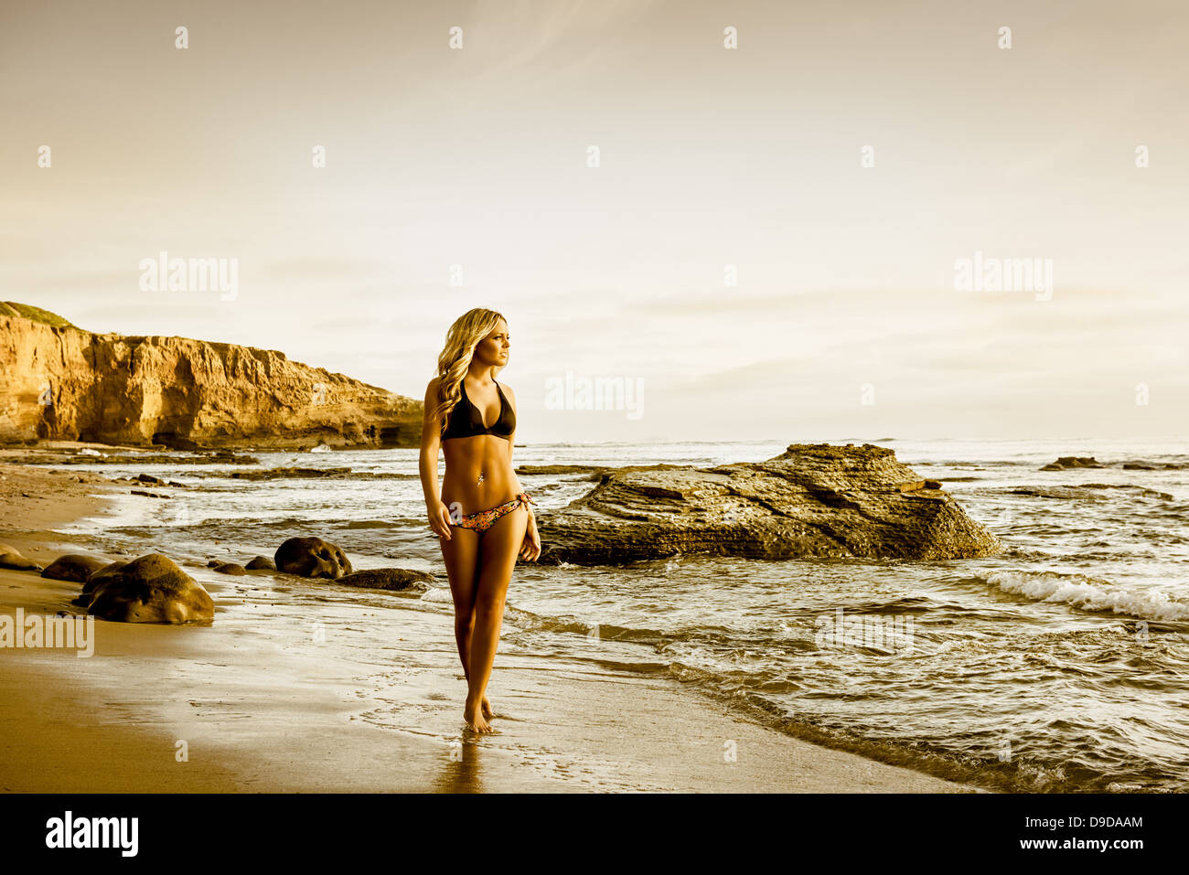 Young woman in bikini walking along beach Banque D'Images
