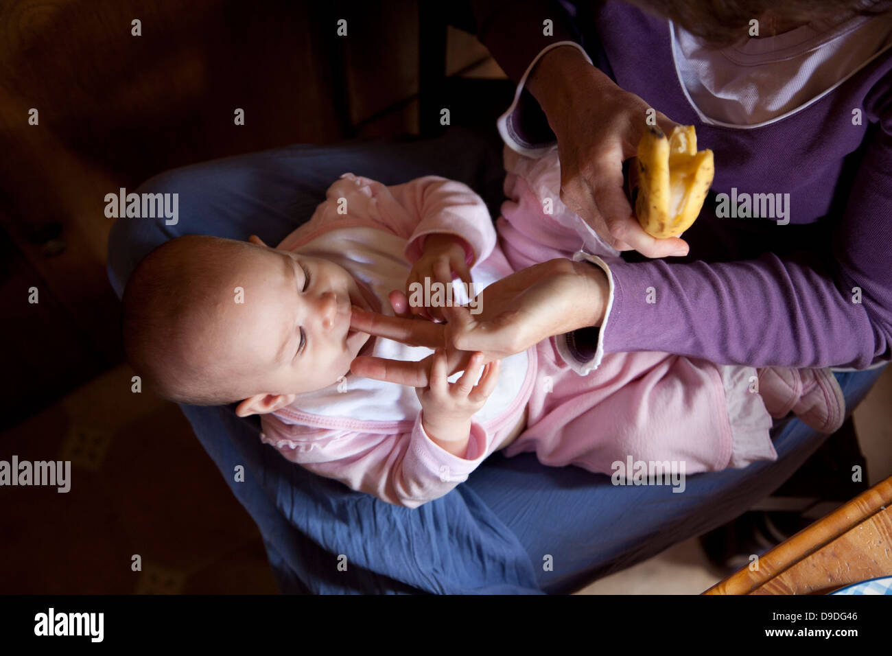 Une mère nourrit son doigt de banane pour bébé âgé d'un an. Banque D'Images