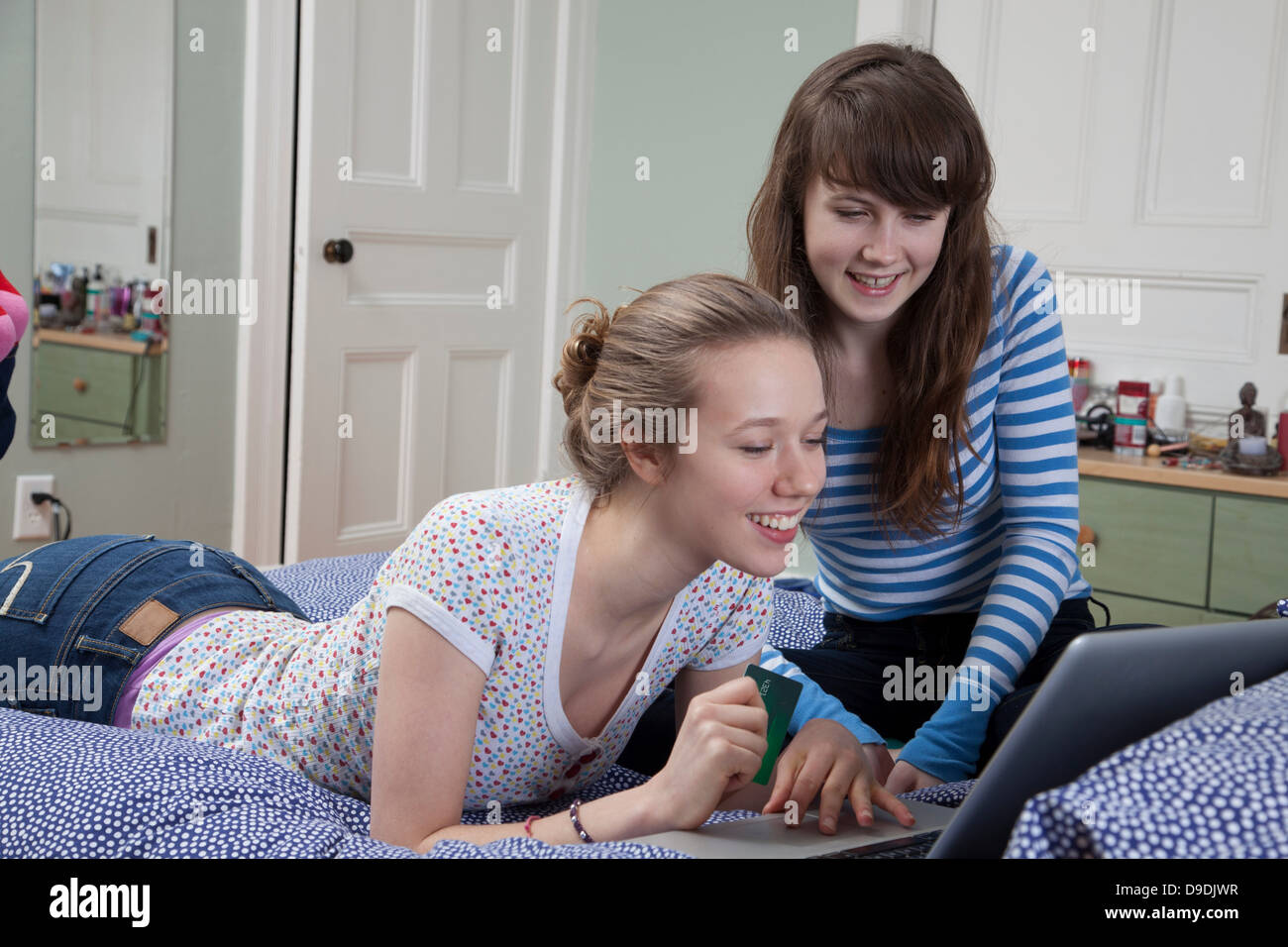 Girls lying on bed with laptop internet shopping Banque D'Images