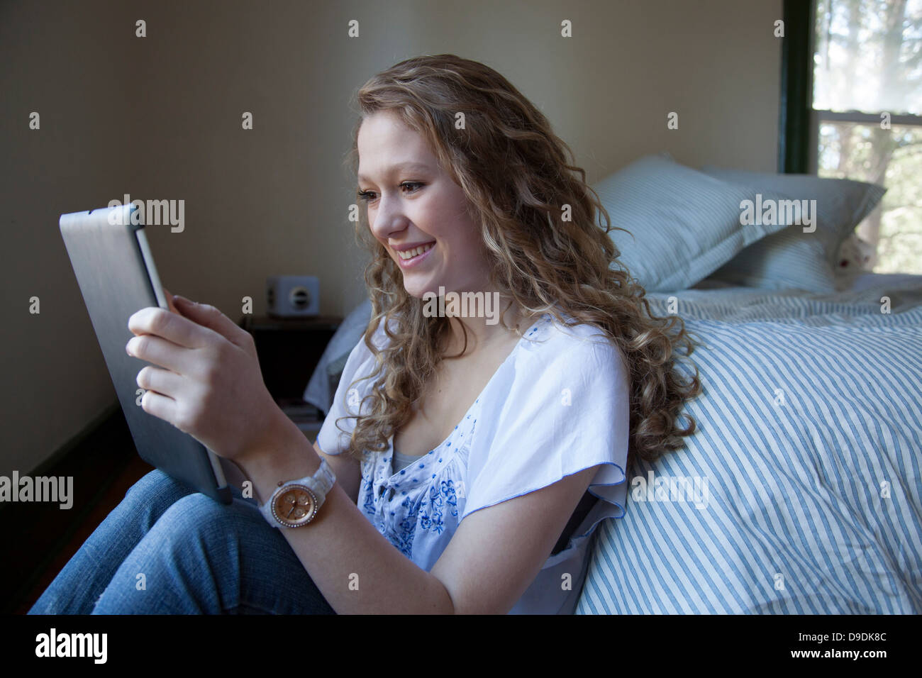 Adolescent sur lit, lecture digital tablet Banque D'Images
