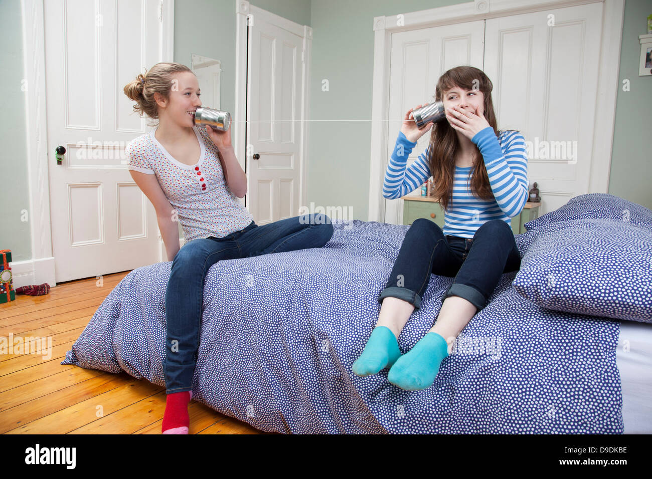 Les filles assis sur le lit à jouer avec tincan téléphone Banque D'Images