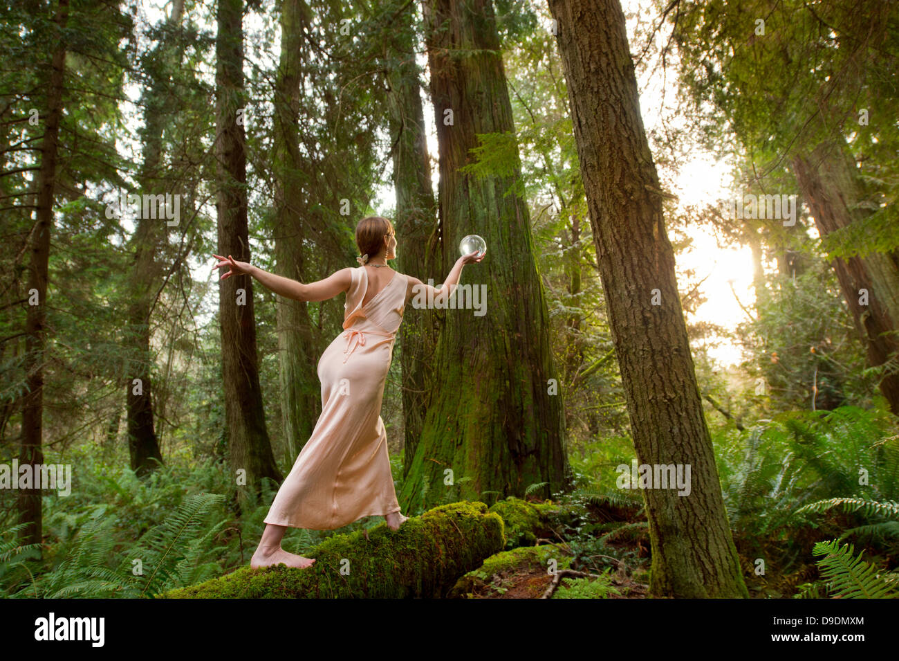 Mature Woman standing on log in forest Banque D'Images