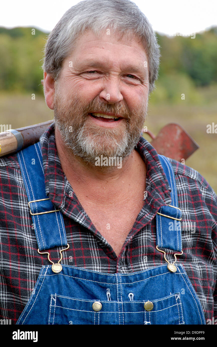 Portrait de barbu aux cheveux gris, vêtu d'agriculteur salopette et chemise à carreaux dans le pré Banque D'Images