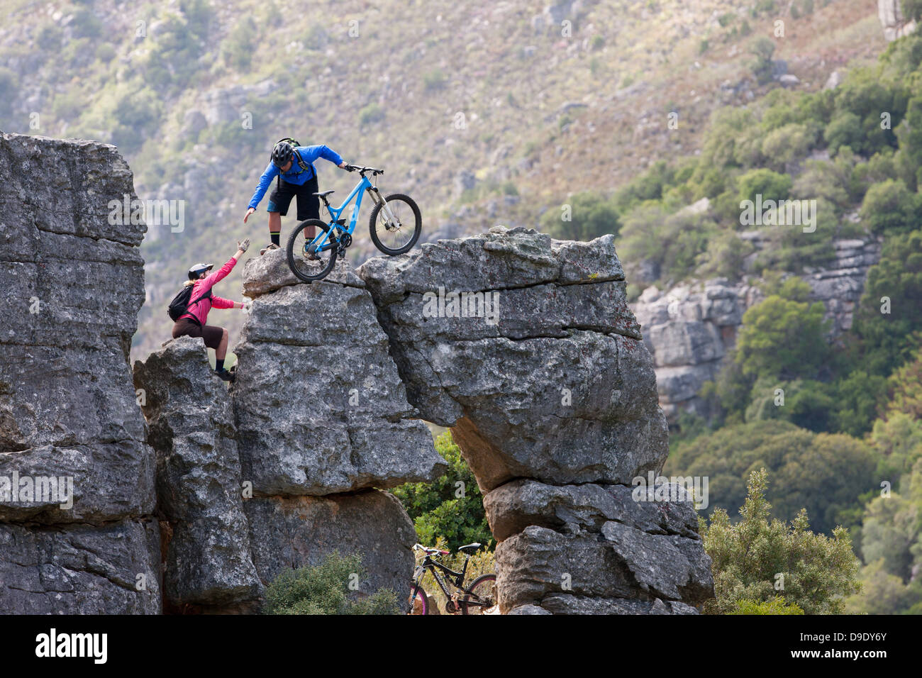 Mountain Biking couple climbing rock formation Banque D'Images