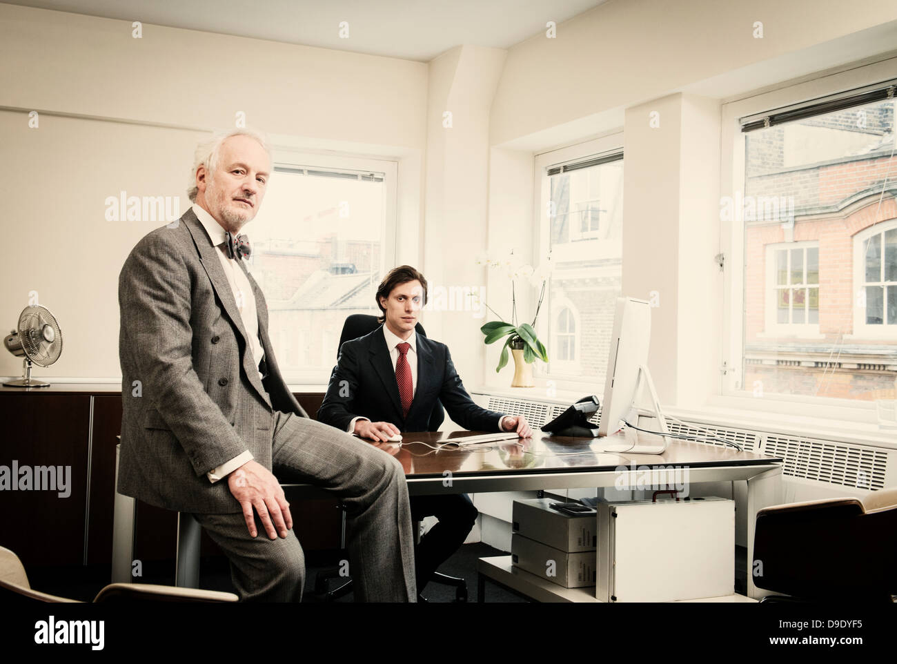 Young businessman at desk with senior man in office Banque D'Images