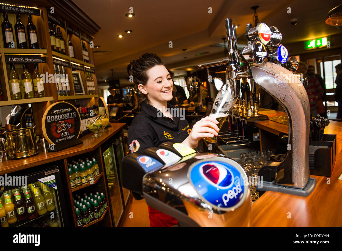 Un travail de barmaid versant une pinte de bière blonde dans un pub bar UK Banque D'Images